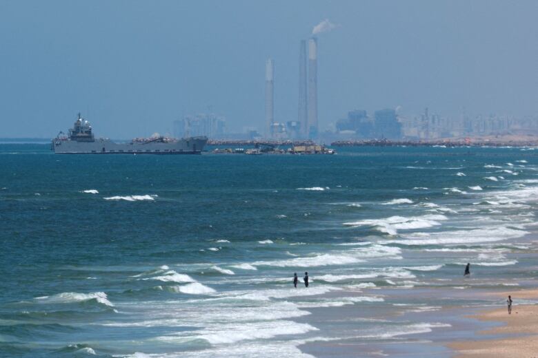 A ship is seen off the coast of a beach.