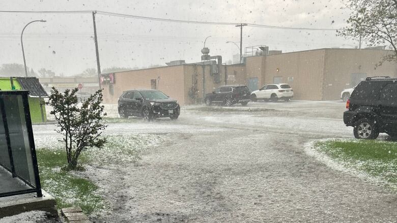 Rain and a hailstorm pounds cars on a street