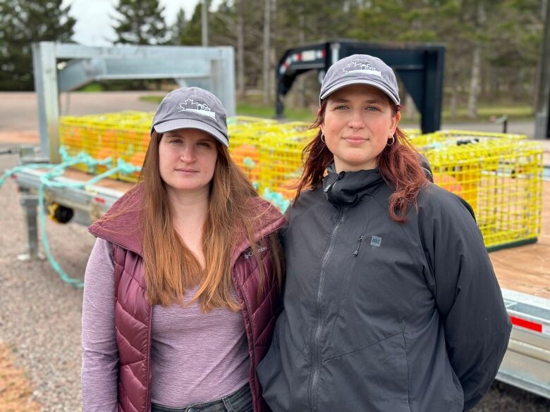 Two women stand in front of fishing traps.