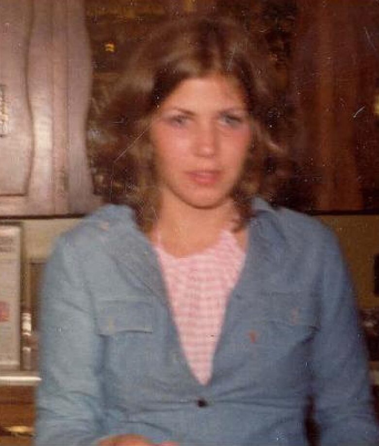 A young woman wearing a blue denim shirt.