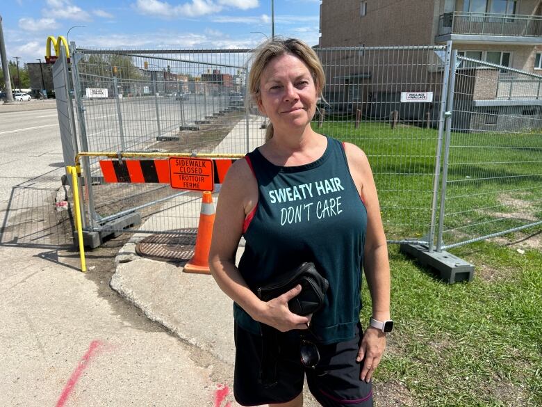 A woman stands in front metal fencing surrounding on apartment building on Portage Avenue.