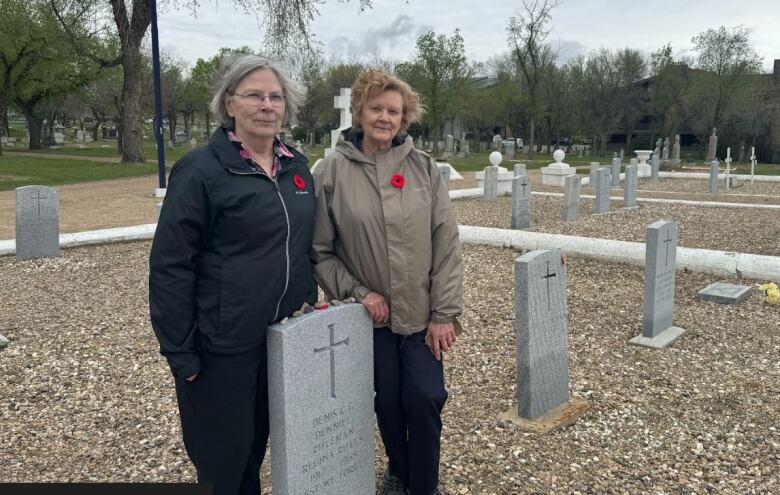 Two woman standing at a gravesite.