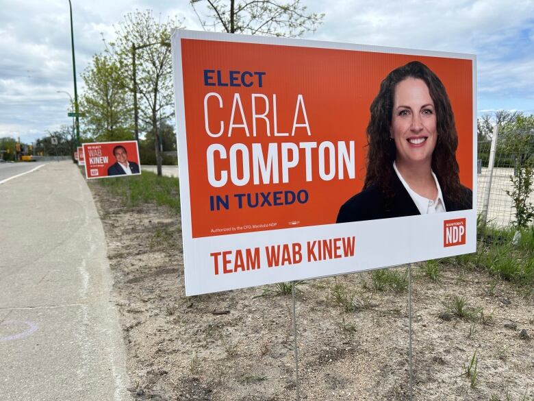 An orange campaign sign with a woman. 