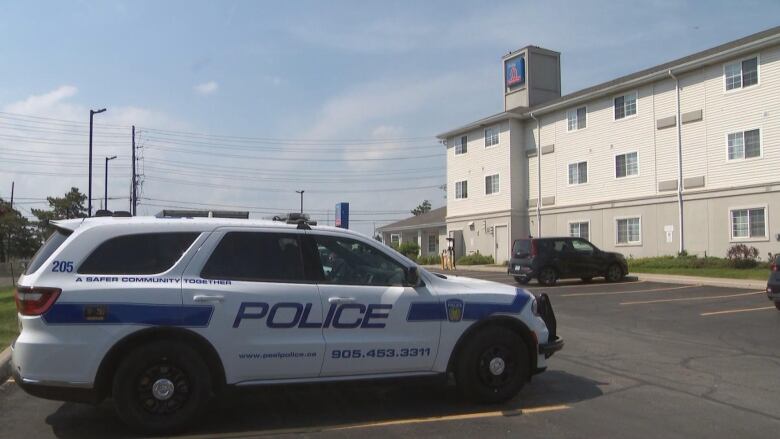 A police SUV sits in the parking lot of a small white hotel. 