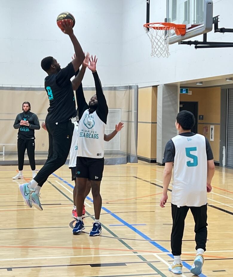 A basketball player jumps to dunk over a teammate at a practice