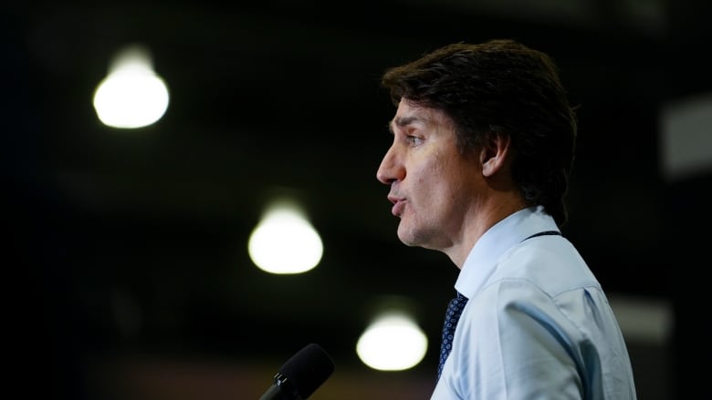 A man in a shirt and tie speaks into a microphone.