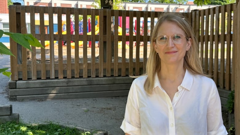 Photo of Niiti Simmonds outdoors in front of a wooden fence with a schoolyard in the background. 