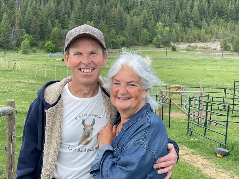 Smiling man in blue jacket stands beside smiling woman in blue jean jacket.