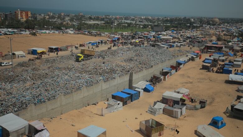 Hundreds of tents are pictured next to a large garbage dump.