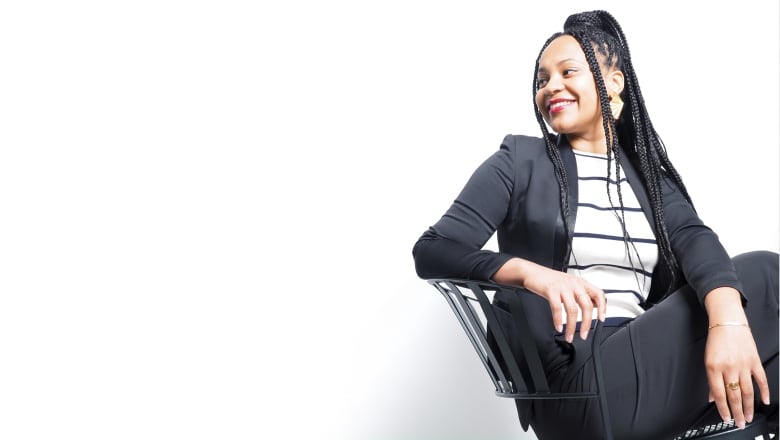 A woman sitting in a chair, smiling and looking off to the side.