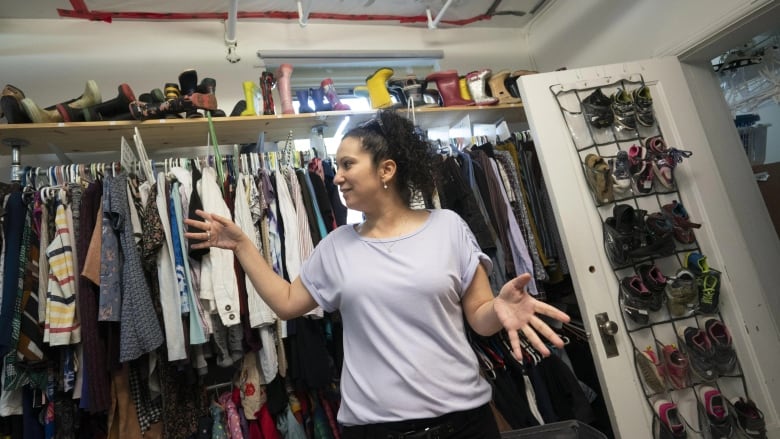 A woman is standing in front of clothes. 