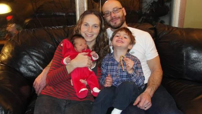 A family sits on a couch smiling.