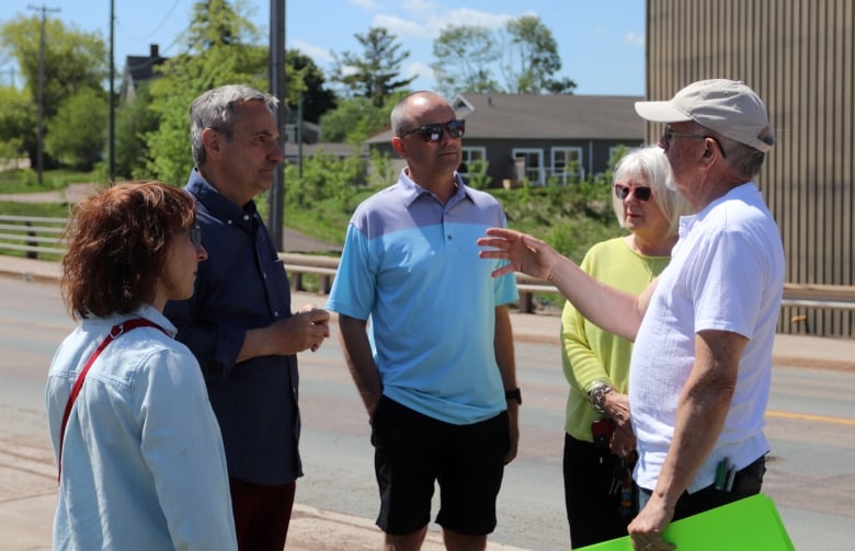 A group of four people listening to a man guesturing.