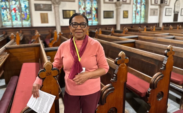 A woman standing by a church pew.