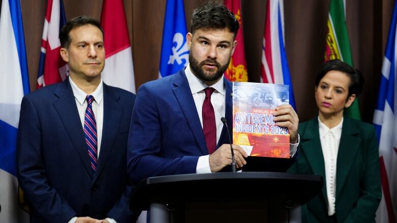 Three people stand by a podium.