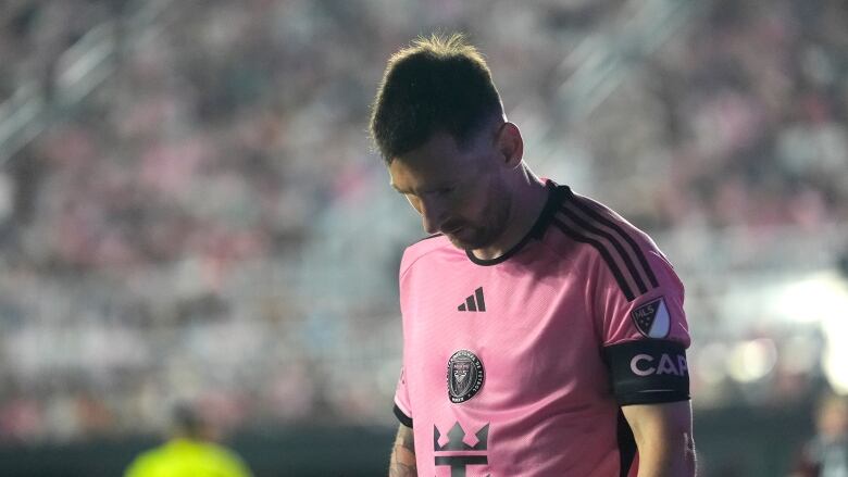 A soccer player wearing pink looks down.