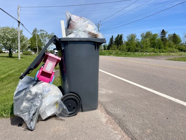 An overflowing black garbage bin.