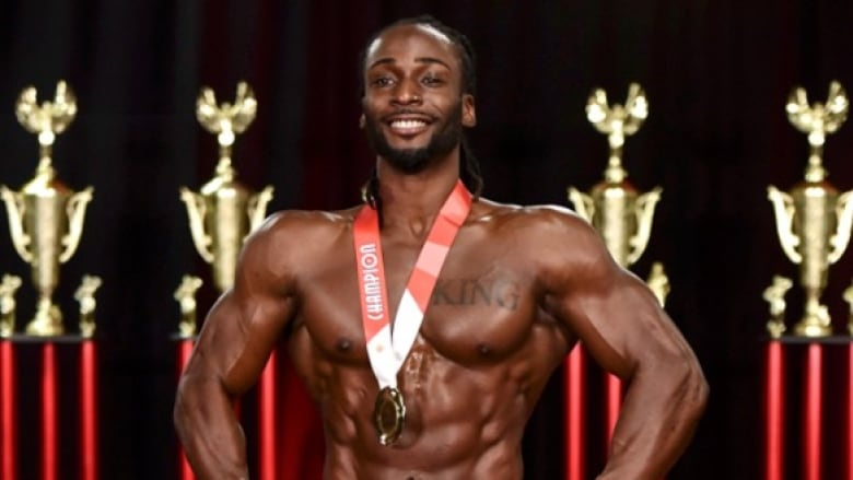 A man poses with a medal in an amateur bodybuilding competition.