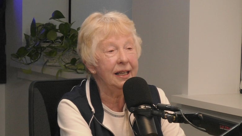 An older woman speaking into a microphone