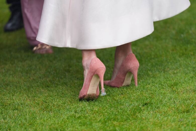 A closeup of the heels on a person's pink stilettos, showing a plastic protector on one.