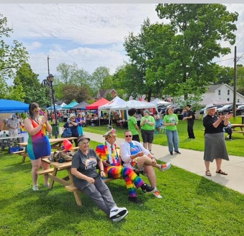 People sit outside in colourful clothing. 