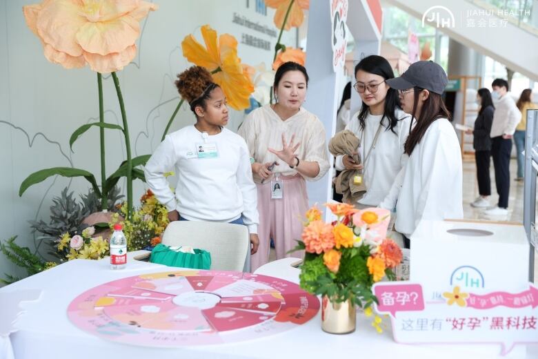 Four young women stand together at a table.