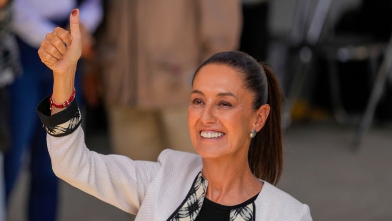 A woman holds her marked thumb in the air after voting.