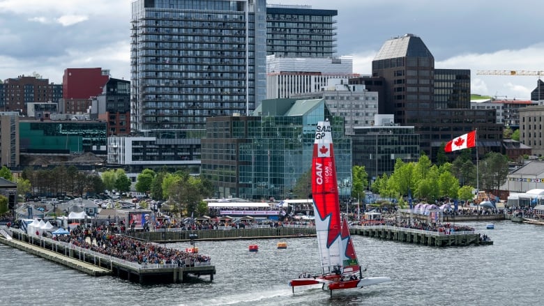 A SailGP boat passes by spectators on the Halifax waterfront.