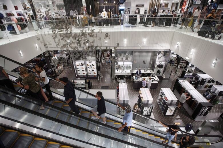 Shoppers ride up the escalator in a large store.