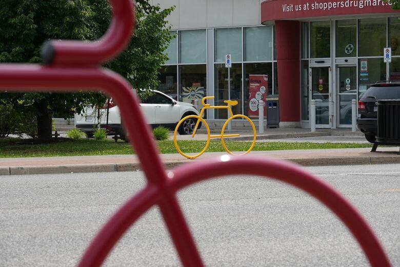 A yellow bike-shaped piece of metal designed for people to lock their bikes to.