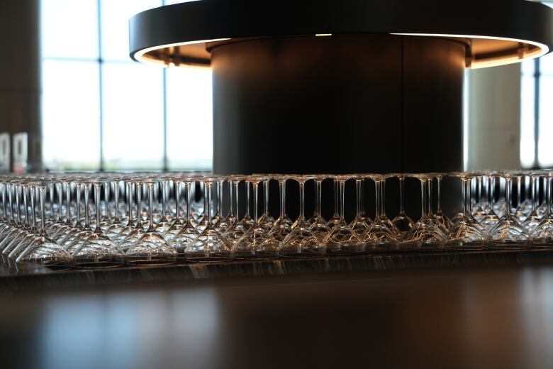 Several cocktail glasses are laid on a bar upside down in a naturally lit room. 