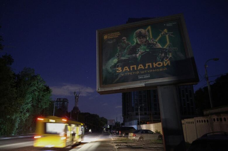 A bus passes by a recruitment billboard for a Ukrainian military brigade in the Ukrainian capital of Kyiv.