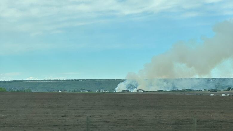 A large plume of smoke is seen in the distance. 