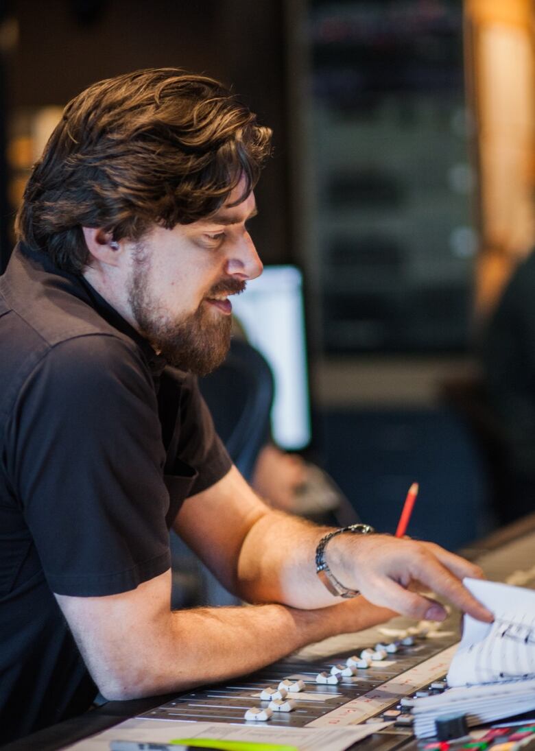 A man sits at a sound board