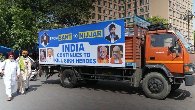 A truck sits outside a building beside a tree. On its side, it says: 'From Sant to Nijjar, India continues to kill Sikh heroes>