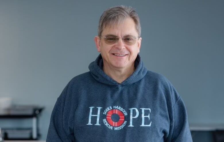 A man in a hoodie saying 'hope' smiles at the camera.