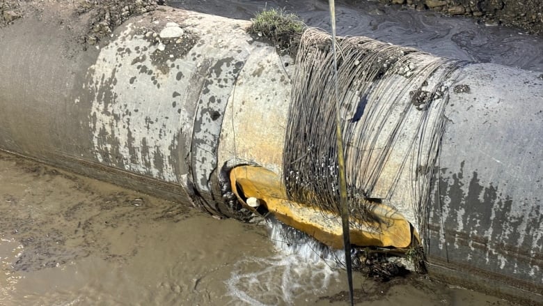 A massive water main pipe is shown, damaged and exposed.