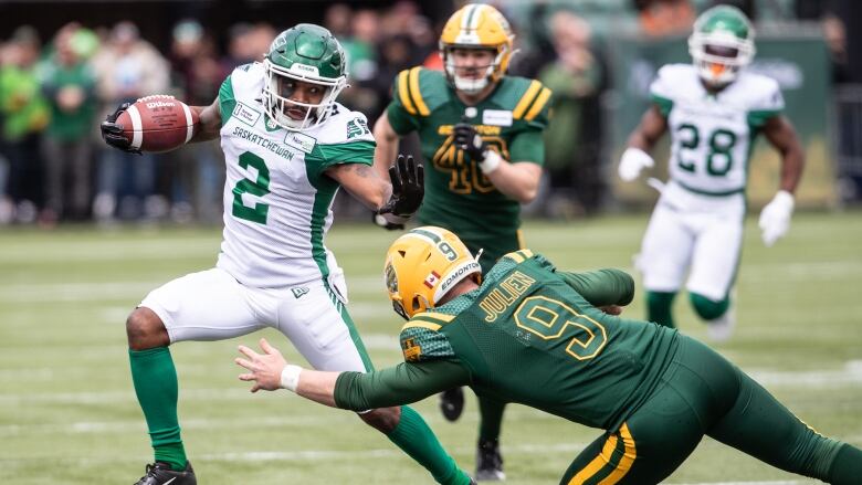 Saskatchewan Roughriders' Mario Alford (2) dodges a tackle from Edmonton Elks' Jake Julien (9).