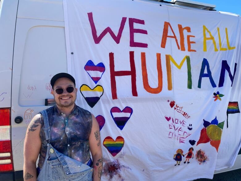 Person stands in front of sign 'We are all human'