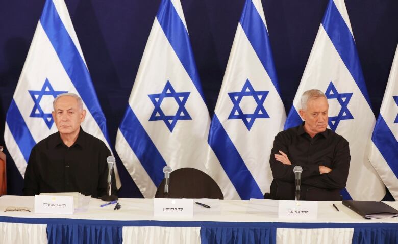 Two people sit at a table with an empty seat between them.