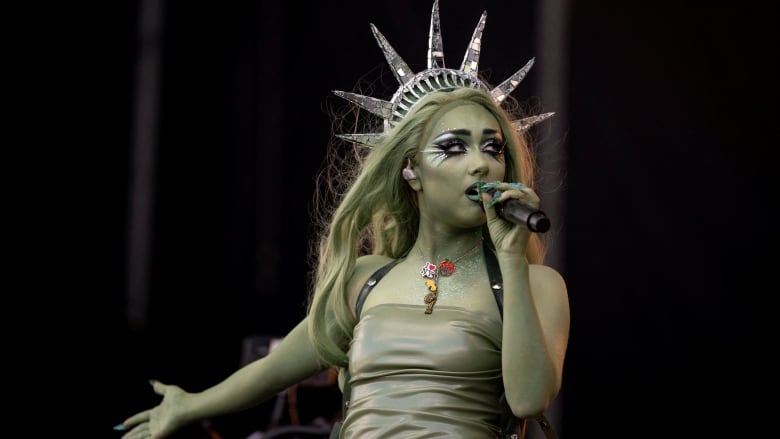 A woman dressed as the Statue of Liberty sings on stage. 