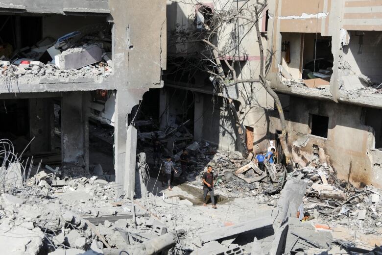 Men walk among debris in the aftermath of Israeli airstrikes.