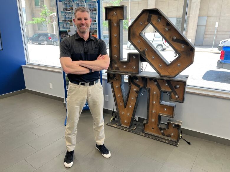 Man standing in tourism office by sign that reads 