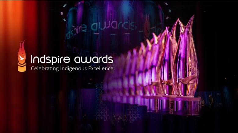 A row of glass-like trophies (shaped like a flame) glimmer in purple, orange and pink hues against a black background. To the left are the words Indspire awards - Celebrating Indigenouse Excellence in white text.