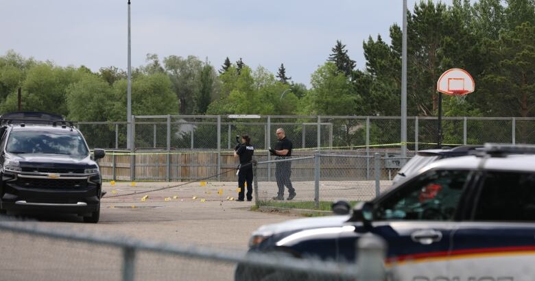 A police cruiser in foreground, two police officers in background, one with a camera.