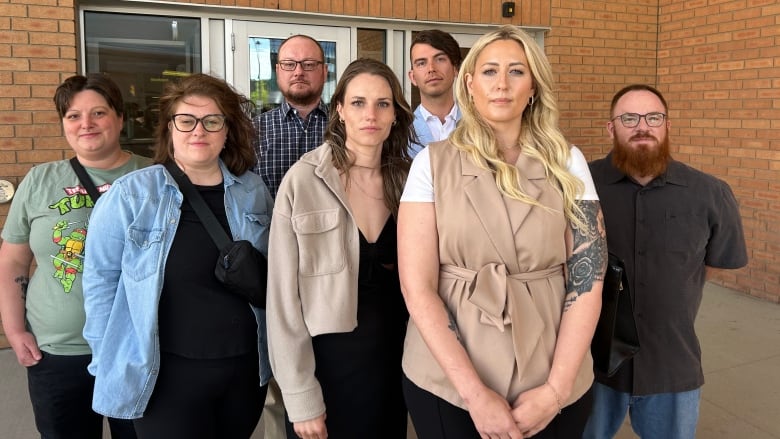 Men and women stand in a group outside a court.