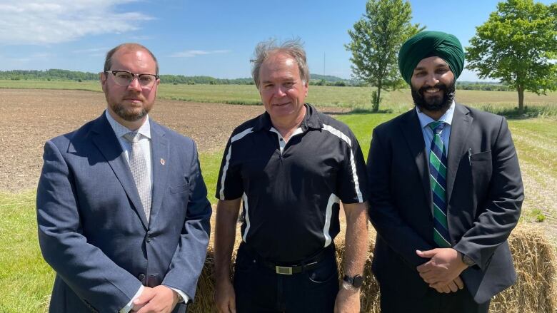 Three men standing in front of farmland