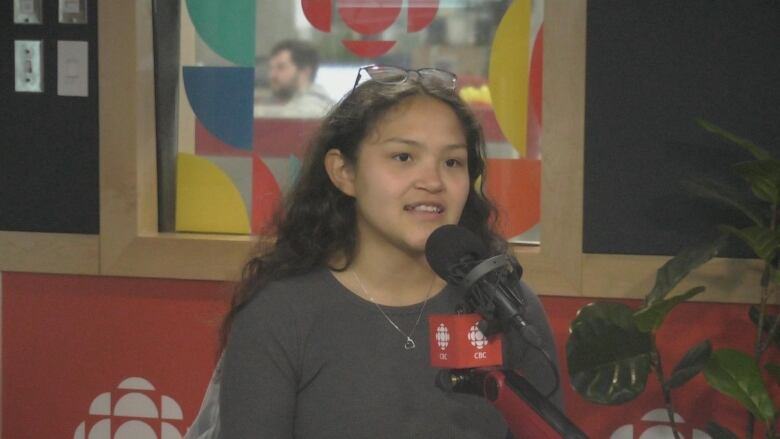 A girl sits at a microphone in a radio studio.