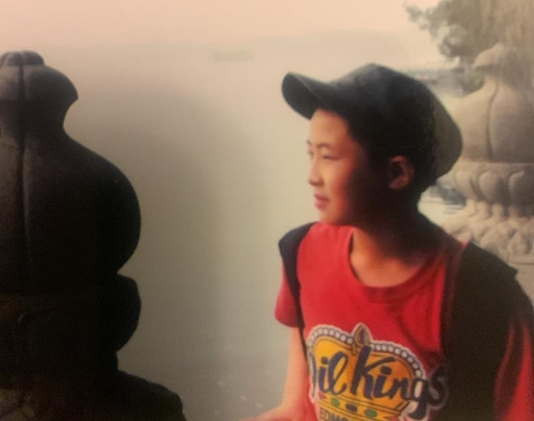 A boy wearing a baseball cap looks off into the distance.