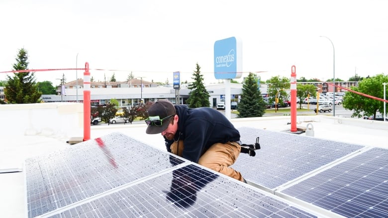 A man with solar panels on a roof.